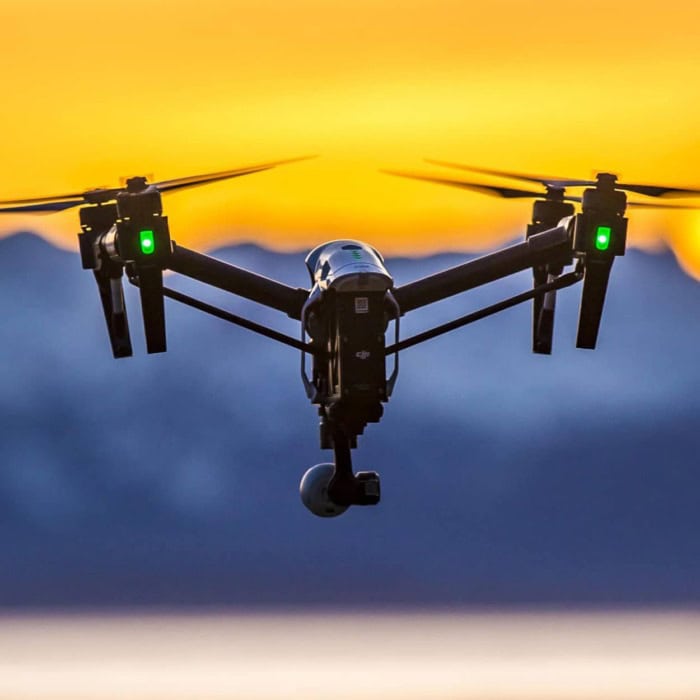 High-quality drone flying at sunset with mountain landscape background.