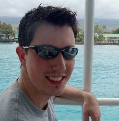Close-up of smiling young man wearing sunglasses by water. Perfect for summer accessories and beachwear.