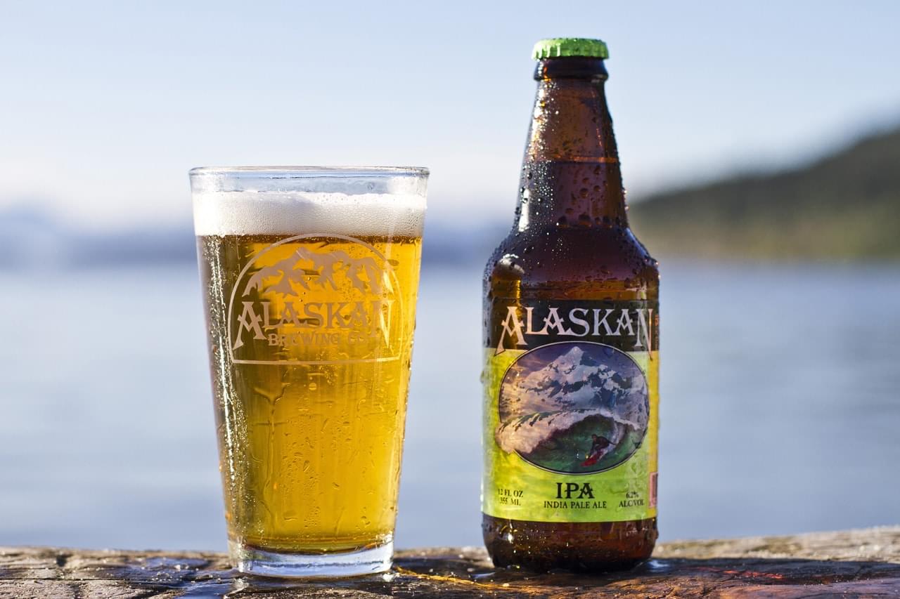 Refreshing Alaska IPA beer on the beach with a scenic ocean backdrop.